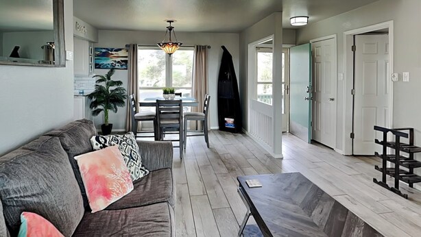 A spacious living area with a gray sofa, a dining table with chairs, a wooden coffee table, and a ceiling light fixture. - Rockport Racquet and Yacht Club by Miss Kitty’s (Rockport)