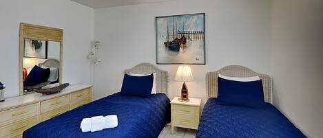 Ein Hotelzimmer mit zwei Betten, einem Spiegel, einem Gemälde, einer Lampe und einem Schminktisch.