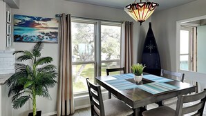 A dining area with a table, chairs, a potted plant, and a view of the outdoors. - Rockport Racquet and Yacht Club by Miss Kitty’s (Rockport)