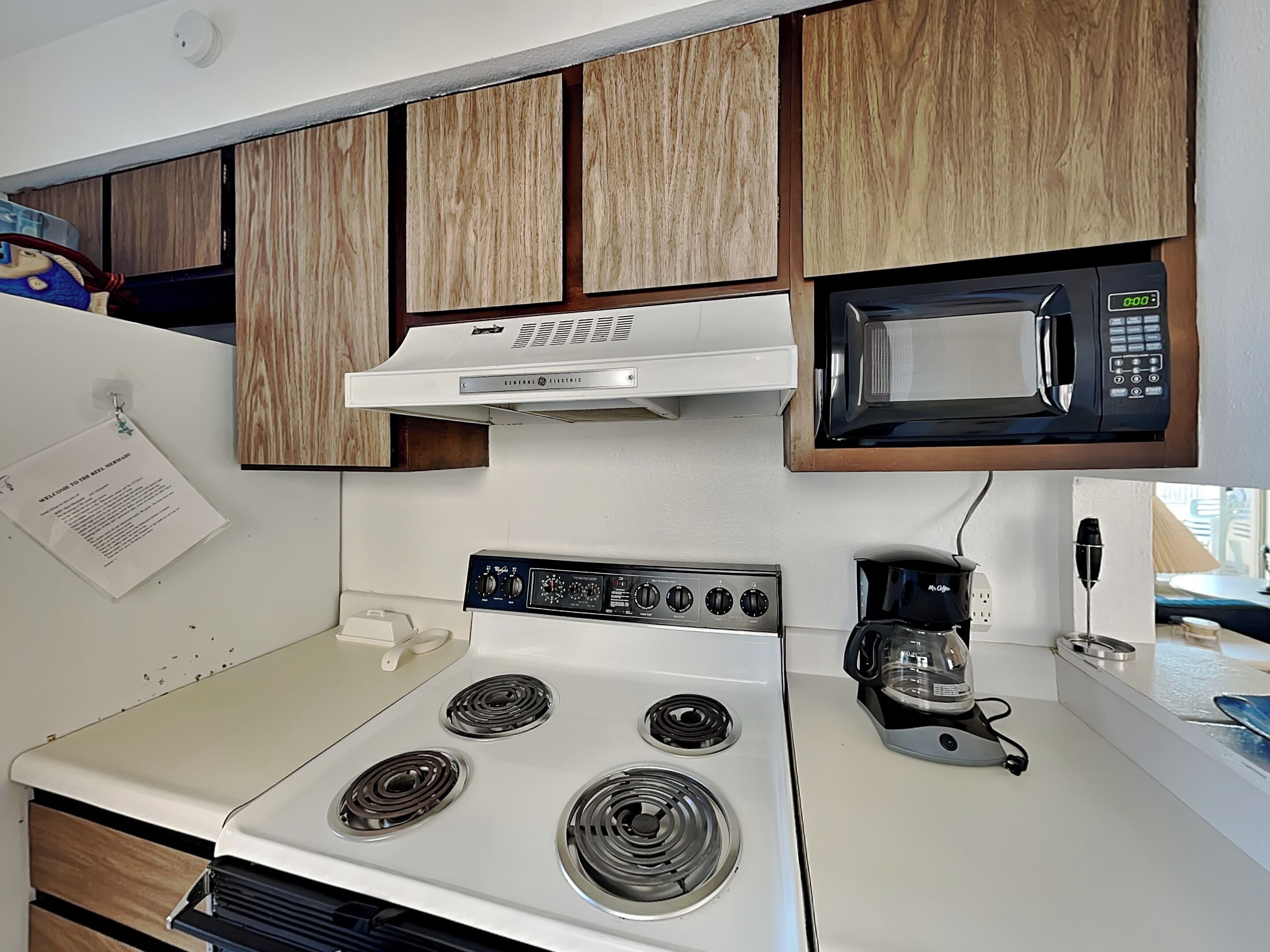 A kitchen with a white stove, a microwave, and wooden cabinets.