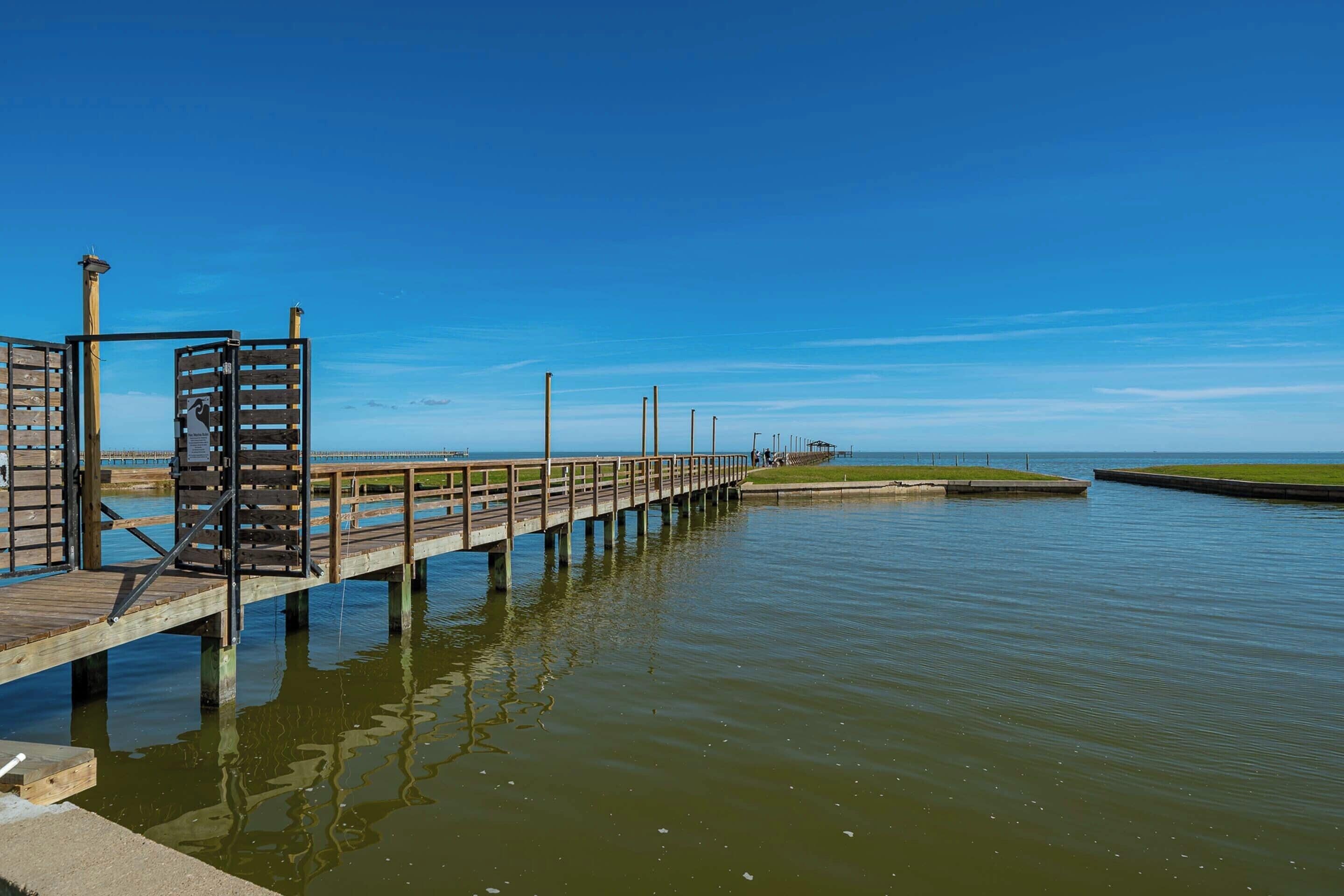 Een houten steiger die zich uitstrekt over een kalm wateroppervlak, met een heldere lucht erboven.