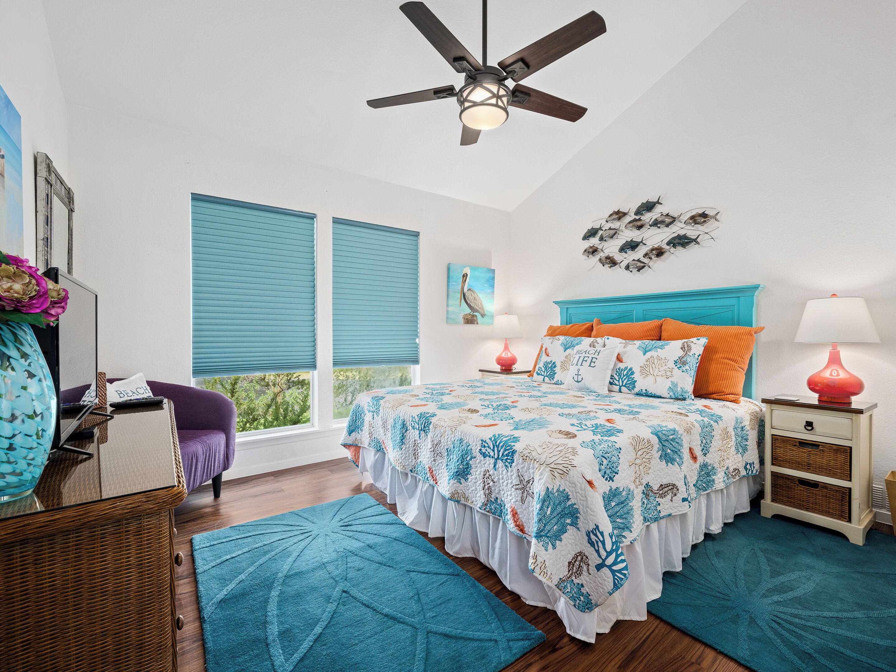 A bedroom with a bed, a desk, a chair, a ceiling fan, and a window with blinds.