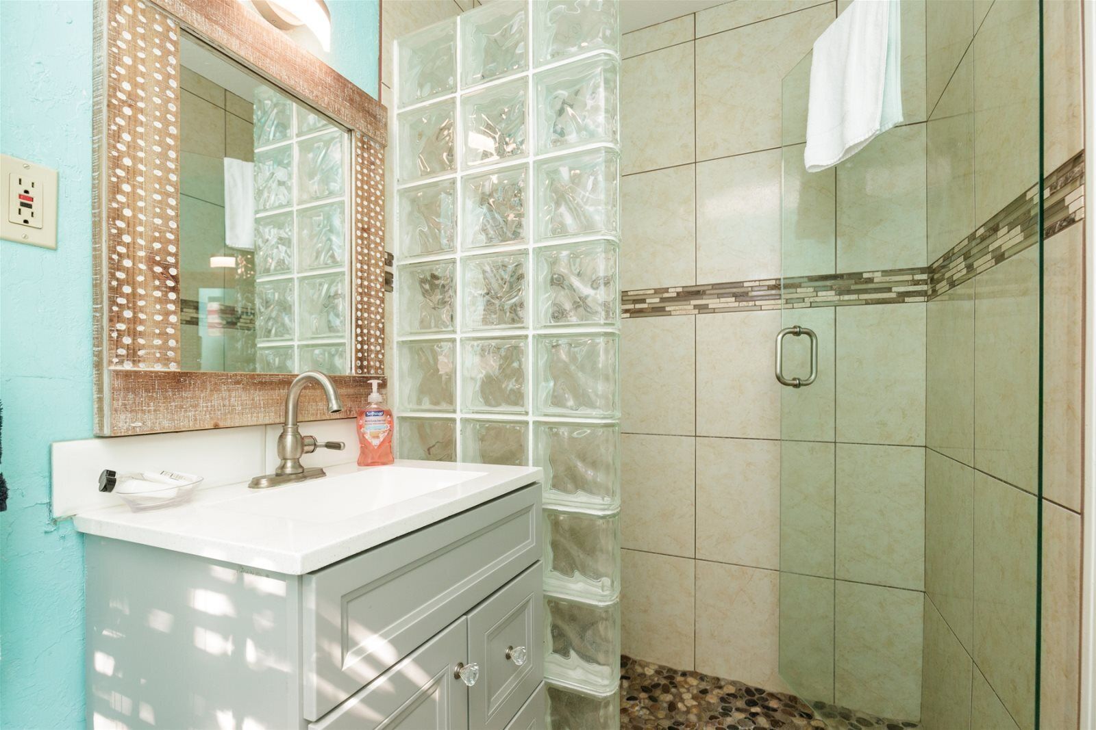 A bathroom with a white vanity, a glass shower enclosure, and a tiled shower area.