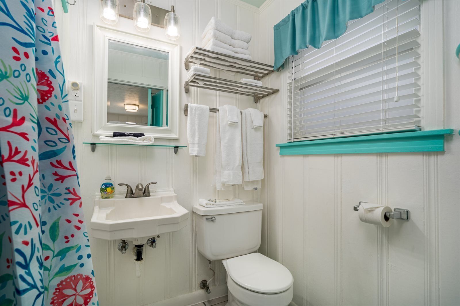 Un bagno con un lavandino bianco, un water, uno specchio e un porta asciugamani.
