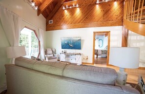 Ein gemütliches Wohnzimmer mit einer großen Couch, einer Holzbalkendecke und einem Gemälde eines Bootes an der Wand.