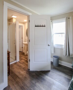 A room with a wooden floor, a white door with a coat rack, a window with curtains, and a visible bathroom with a toilet and sink. - Deep Water Dock and Home on the GA Coast (Midway)