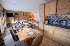 Uma cozinha compacta com armários de madeira, uma mesa de jantar posta para quatro pessoas e uma máquina de café.