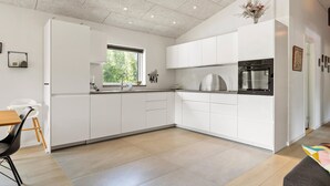 A modern kitchen with white cabinetry, a built-in oven, and a window with a view of greenery.