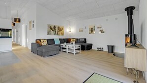 A modern living room with a grey sofa, a white coffee table, and a black fireplace.