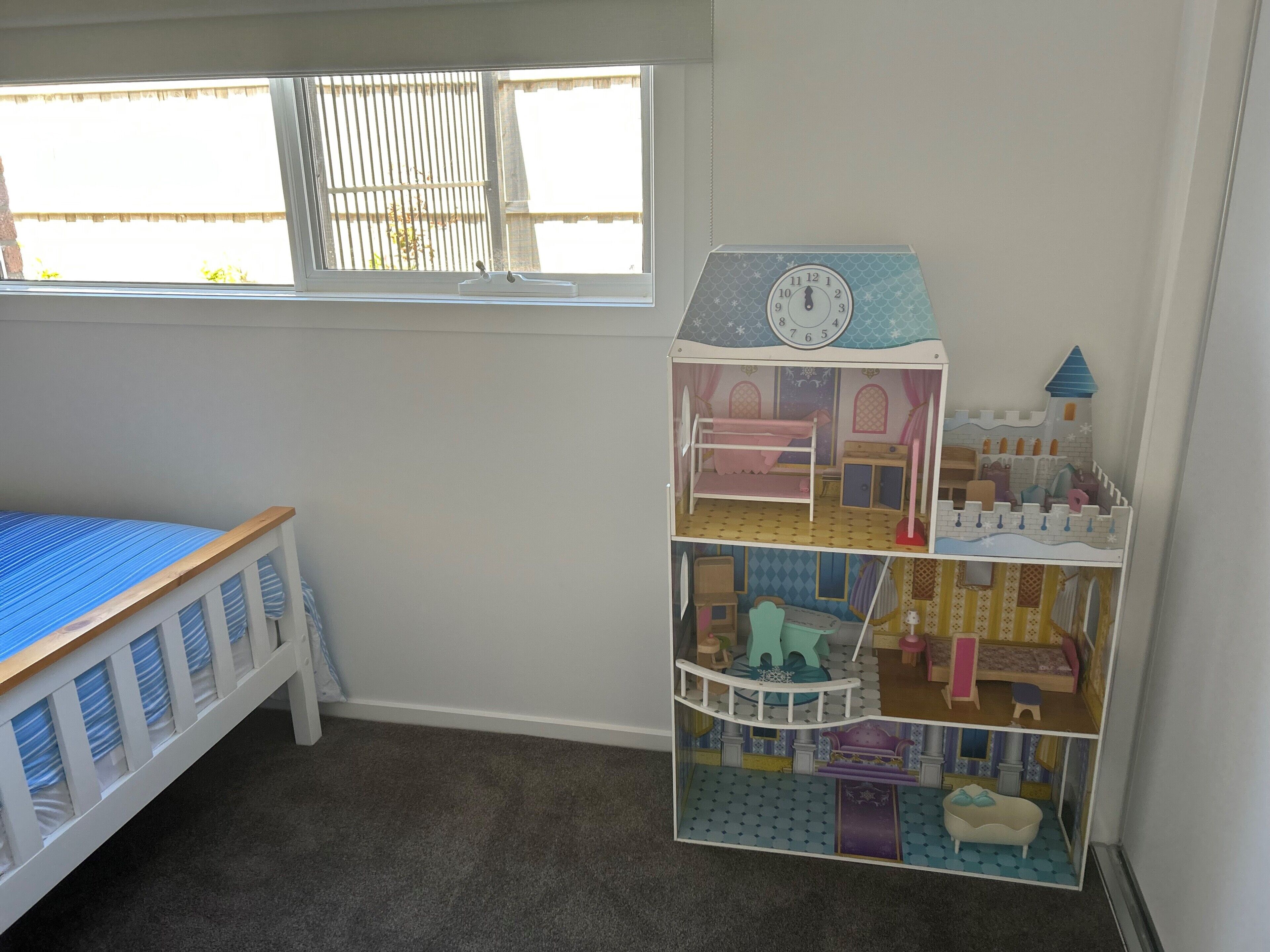 A child's room with a bunk bed, a window with blinds, and a multi-level dollhouse.