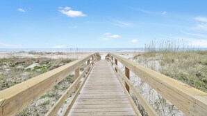 A wooden boardwalk leading to a beach with sand and sparse vegetation. - St Augustine Beach Condo just steps from the beach! (St. Augustine)