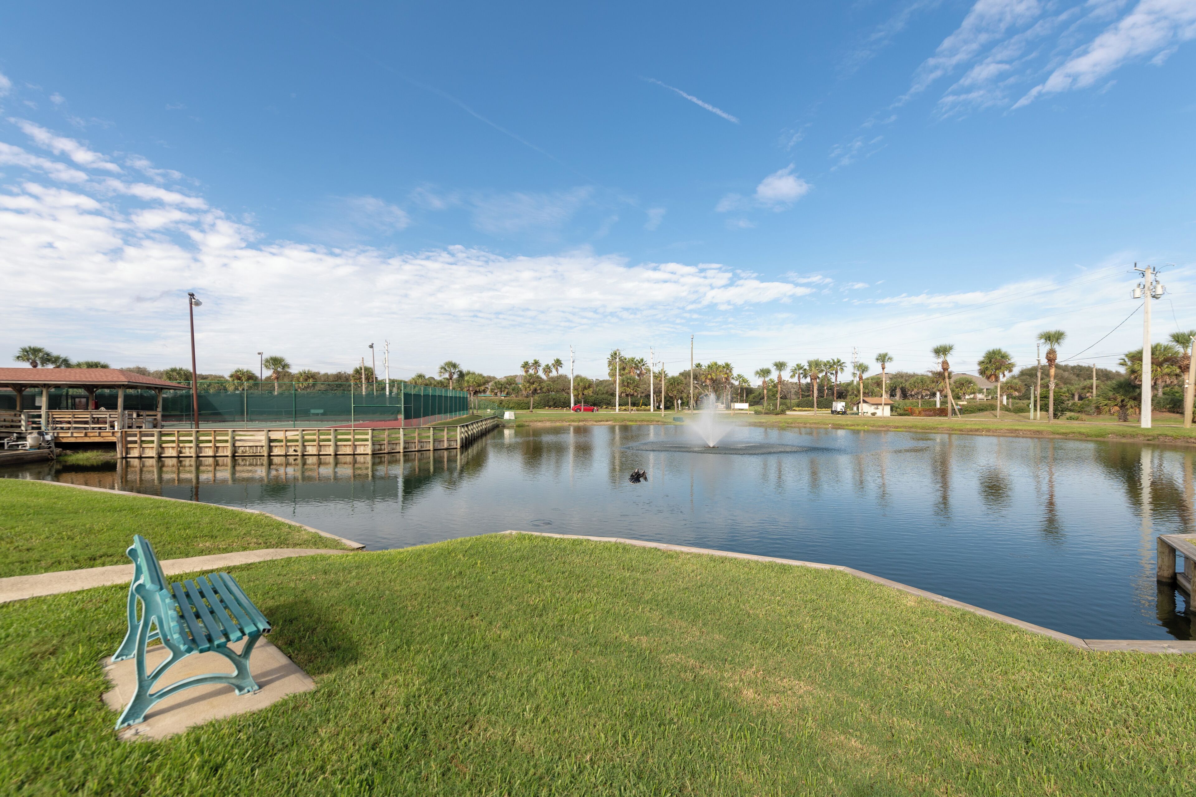 A park with a pond, a bench, and a gazebo.