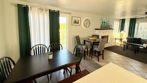 Een eetgedeelte met een tafel en stoelen, een open haard en een bank in een woonkamer.