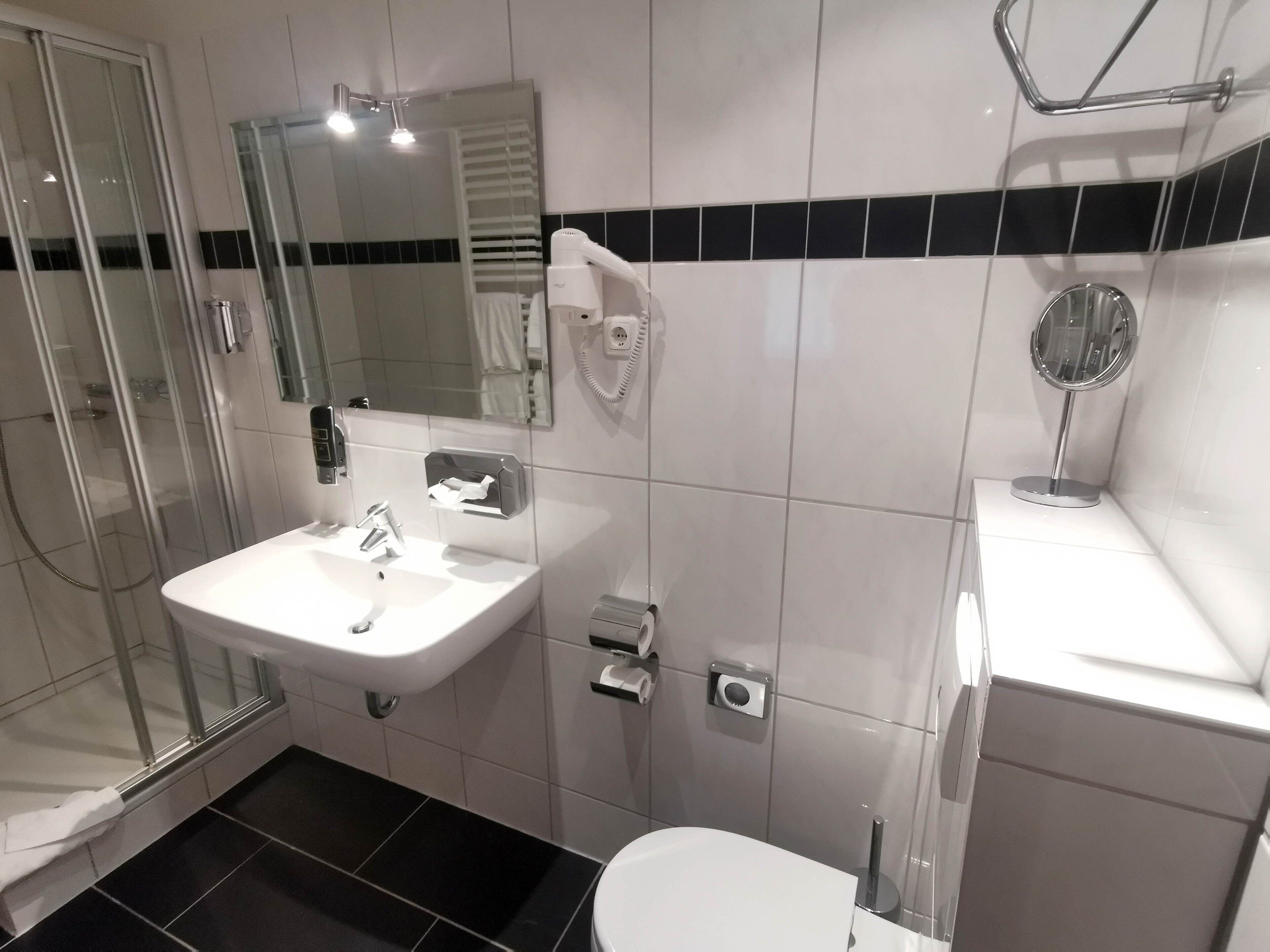 Ein modernes Badezimmer mit Duschkabine, Waschbecken mit Spiegel und Toilette.
