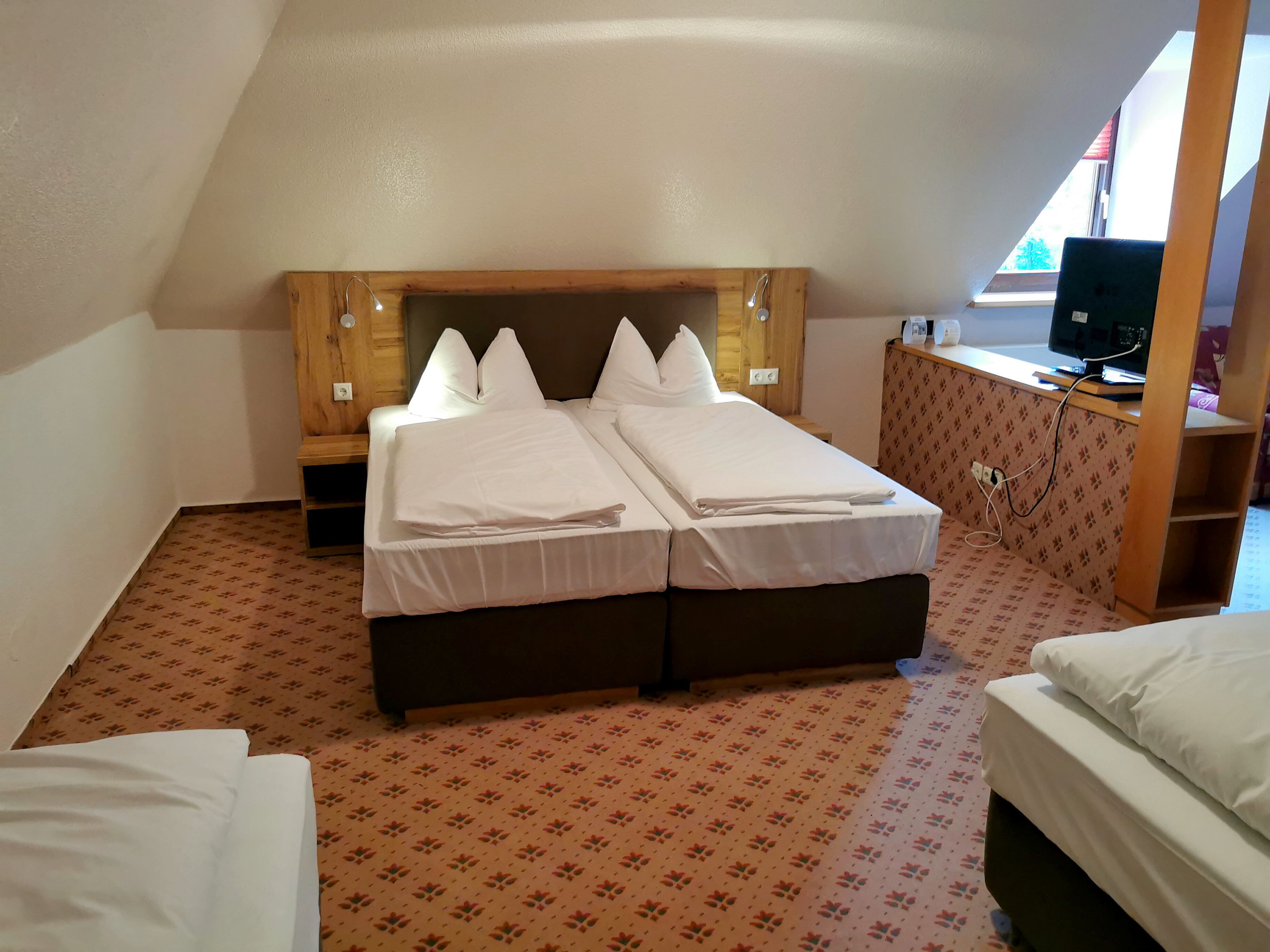 A room with a double bed, a small desk, and a television.