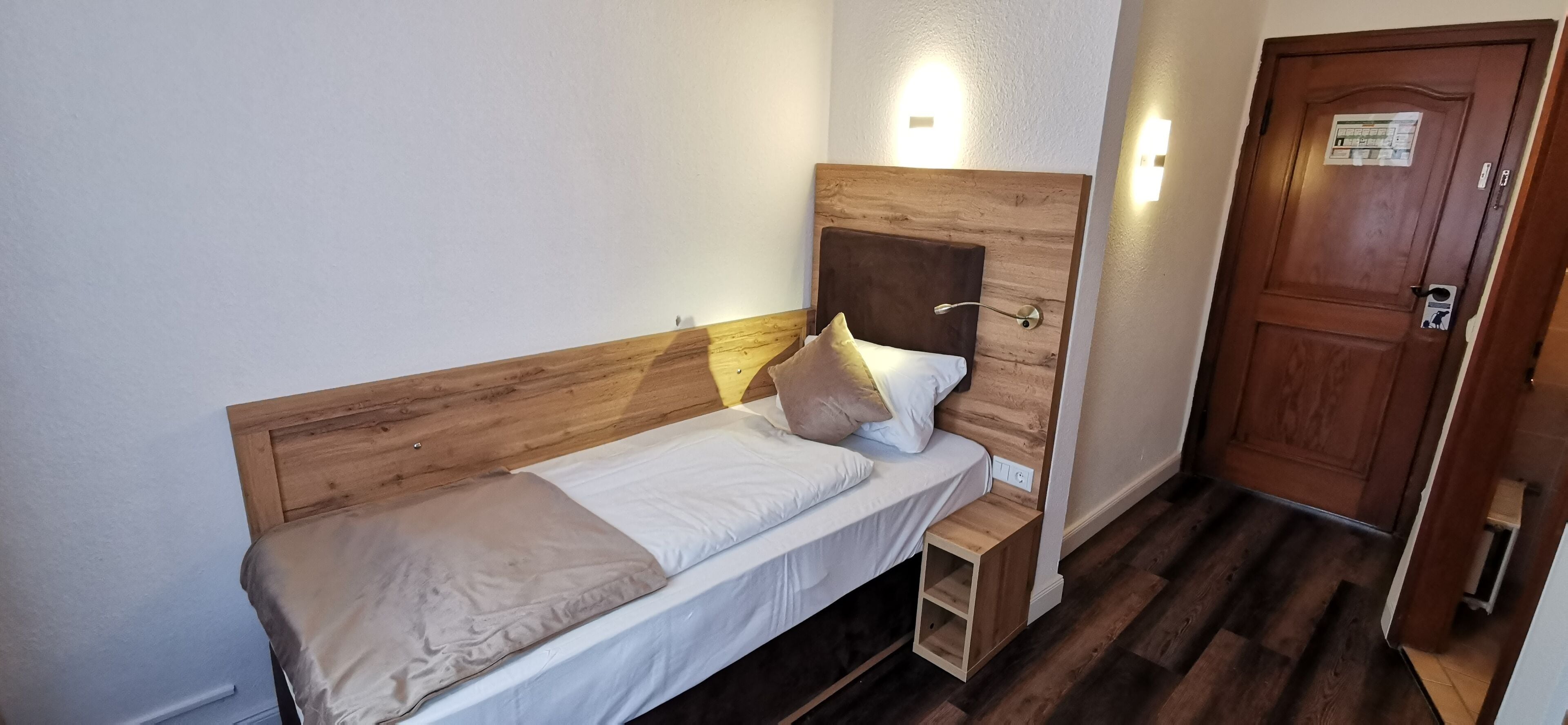 A single bed with a wooden headboard, a bedside table, and a nightstand.