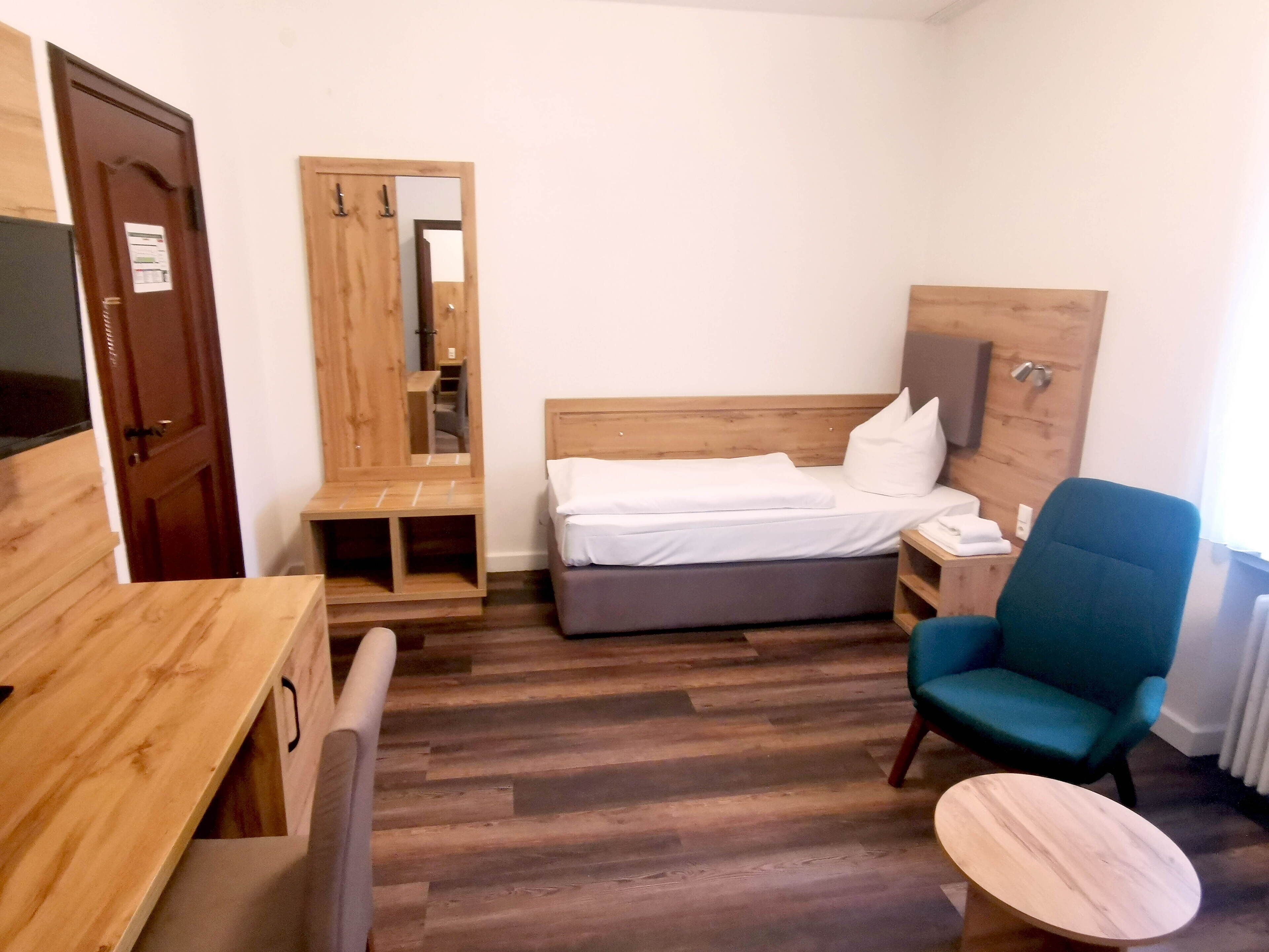 Una habitación de hotel con una cama de madera, un escritorio, una silla y una pequeña mesa.