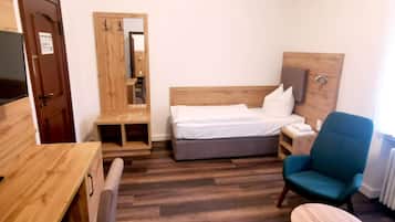 A hotel room with a wooden bed, a desk, a chair, and a small table.