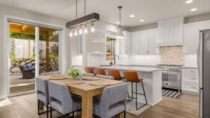 A modern kitchen with white cabinets, a wooden dining table, and a built-in island.