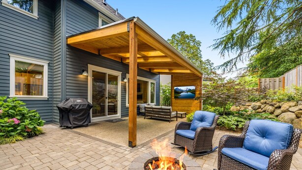 A covered patio with a fire pit, outdoor furniture, and a stone fire pit.