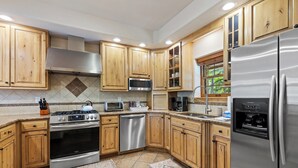 A modern kitchen with wooden cabinets, stainless steel appliances, and a built-in microwave.