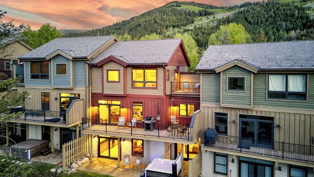 A multi-story residential building with a balcony, outdoor seating area, and a hot tub.