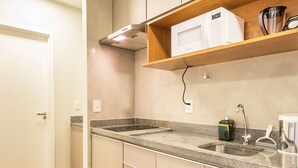 Een kleine keuken met een granieten aanrechtblad, een roestvrijstalen spoelbak en houten planken erboven.