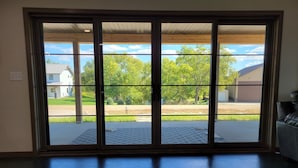 Ein Zimmer mit einer großen Schiebeglastür, die zu einem überdachten Außenbereich mit Blick auf eine Wohngegend und einen Rasen führt.