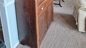 Une pièce comprenant un grand meuble en bois, un canapé beige et une petite table ornée d’objets décoratifs.