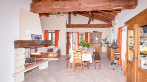 A rustic interior with a stone fireplace, wooden beams, a dining area with a table and chairs, and a cabinet with books. - Nice home in St Andrea Di Cotone (St Andrea Di Cotone)