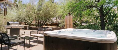 An outdoor patio with a hot tub, a grill, and seating.