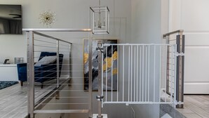 Et moderne værelse med en metaldør, en seng med blåt sengetøj og et billede på væggen.