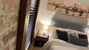 A bedroom with a bed, a nightstand, a lamp, and three airplane paintings on the wall. - Heart of Downtown 1 BR/1 BA - Hidden Gem (Norfolk)