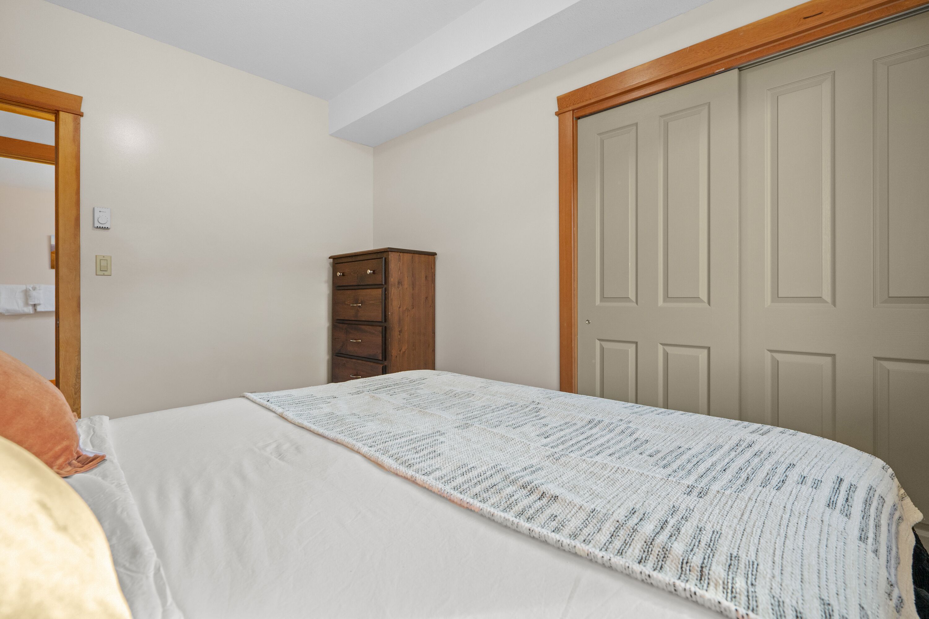 Une chambre à coucher avec un lit, une commode en bois et une porte.
