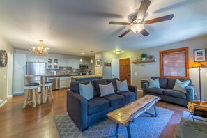 A spacious living room with a dark blue sofa, wooden coffee table, and a ceiling fan.