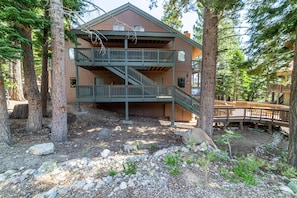 A multi-story building with a balcony and a staircase, surrounded by trees.
