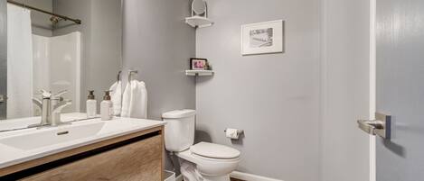 A modern bathroom with a wooden vanity, white fixtures, and a gray wall.