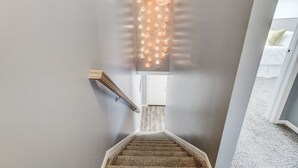 Una escalera con barandilla, escalones alfombrados y una pared decorada con luces y farolillos de papel.