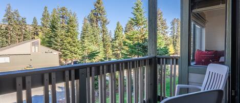 A balcony with a view of tall trees and a building in the background.