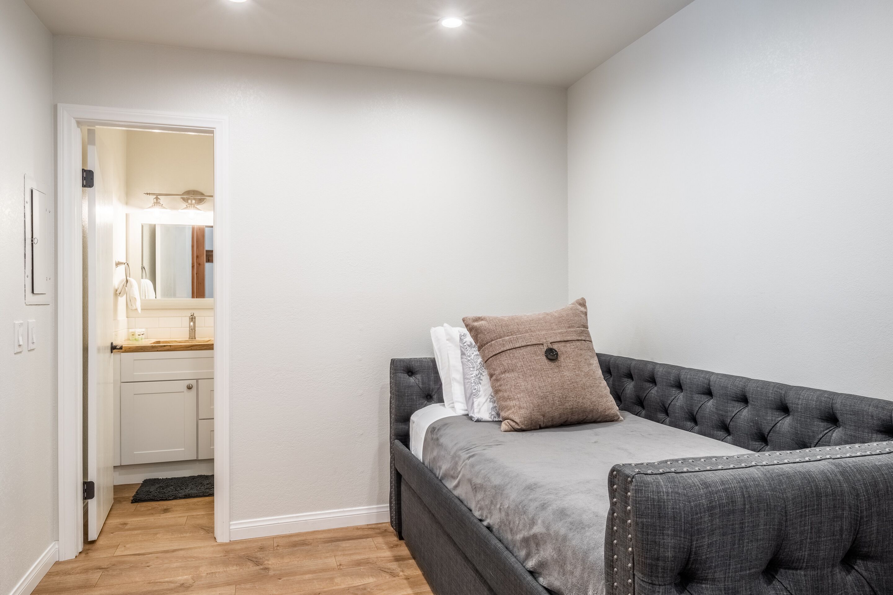 Een slaapkamer met een bed, een nachtkastje en een klein bureau met een spiegel.