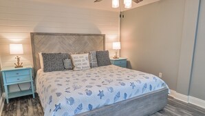 Ein Schlafzimmer mit einem großen Bett, zwei Nachttischen und einem Deckenventilator.