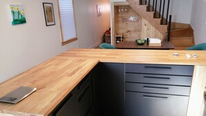 Une cuisine dotée d’un plan de travail en bois, de meubles de rangement noirs et d’un lave-vaisselle encastré.