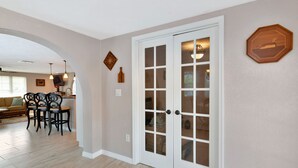 A room with a large white door with glass panels, a dining area with a table and chairs, and a kitchen area with a countertop and appliances. - Beautiful, Spacious Heated Pool Home - Close to Siesta Key Beach! (Sarasota)