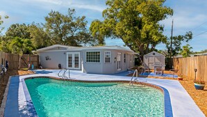 A backyard with a swimming pool, a small house, and a wooden fence. - Beautiful, Spacious Heated Pool Home - Close to Siesta Key Beach! (Sarasota)