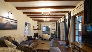 Una sala de estar acogedora con chimenea, vigas de madera y un ventanal con cortinas.