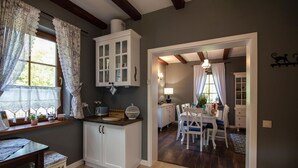 Una cocina con armarios blancos, un comedor con mesa y sillas, y un pasillo que conduce a otra habitación.