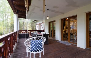 Eine Holzterrasse mit einer Hängematte, einem Tisch und Blick auf den Wald.