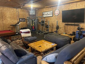 A gym with exercise equipment, a television, and a pool table.