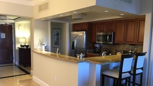 Una cocina moderna con una isla central, electrodomésticos de acero inoxidable y taburetes de bar.