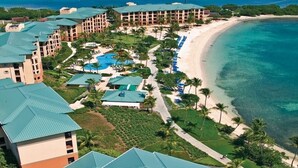 Un resort con varias construcciones, playa y piscina.